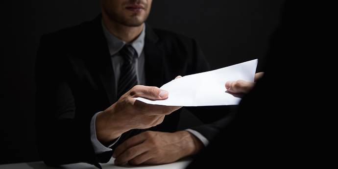 Two men trading documents in a dark room