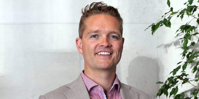 Sam Johnson smiling, wearing shirt and grey jacket.