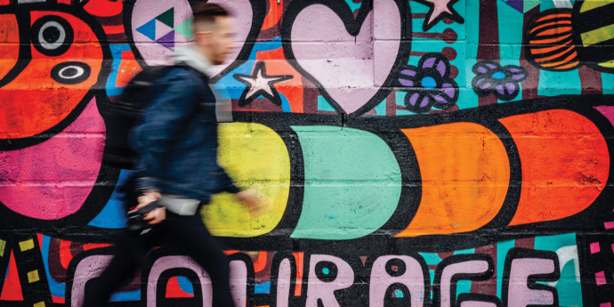 man walking past a graffiti wall  