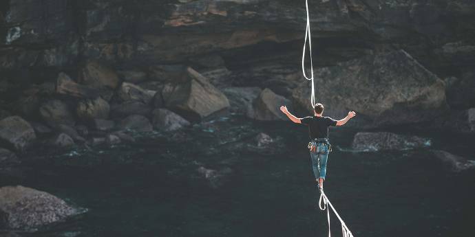 man walking a tightrope across a ravine