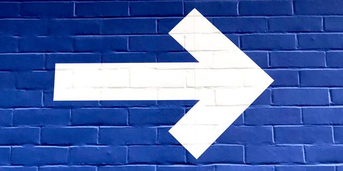 white arrow painted on blue brick wall